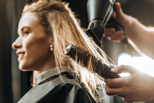 primo piano vista parziale di pettinatura parrucchiere e asciugatura dei capelli alla bella giovane donna nel salone di bellezza
 - Foto, immagini