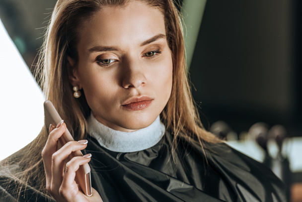 beautiful young woman using smartphone in beauty salon - Foto, Imagen