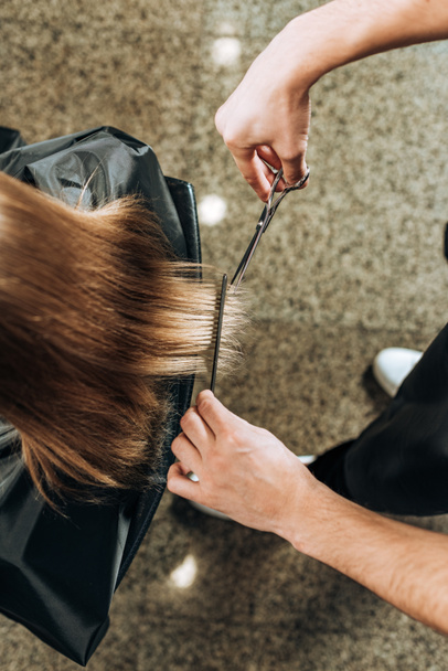 vista dall'alto parziale dello scatto ritagliato del parrucchiere che taglia i capelli alla giovane donna nel salone di bellezza
 - Foto, immagini
