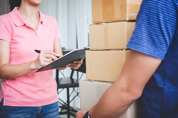 Home delivery service and working with service mind, Woman customer signing and receiving a cardboard boxes parcel from deliveryman. - 写真・画像