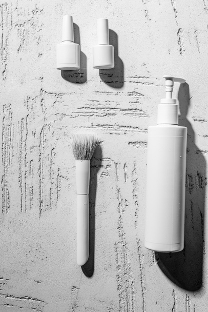 vista de cerca de esmaltes de uñas decorativos blancos, cepillo y contenedor en la pared en el salón de belleza
 - Foto, Imagen