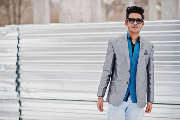 Casual young indian man in silver jacket and sunglasses posed against steel background. - Foto, Bild