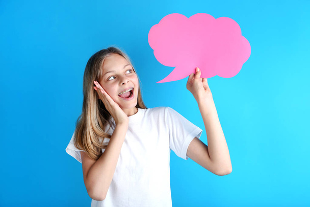 Young girl holding speech bubble on blue background - Foto, Imagen