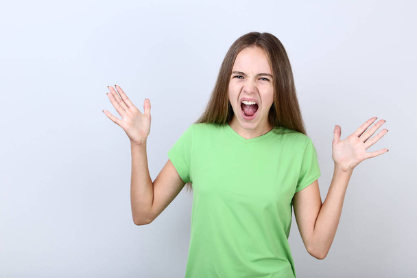 Young screaming girl on grey background - Fotografie, Obrázek
