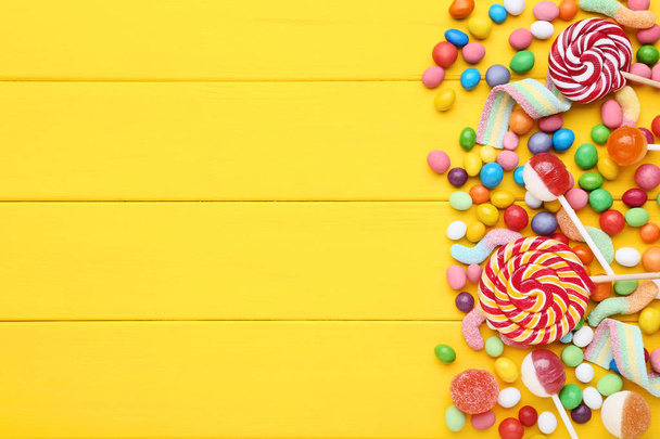Sweet candies and lollipops on yellow wooden table - Photo, Image