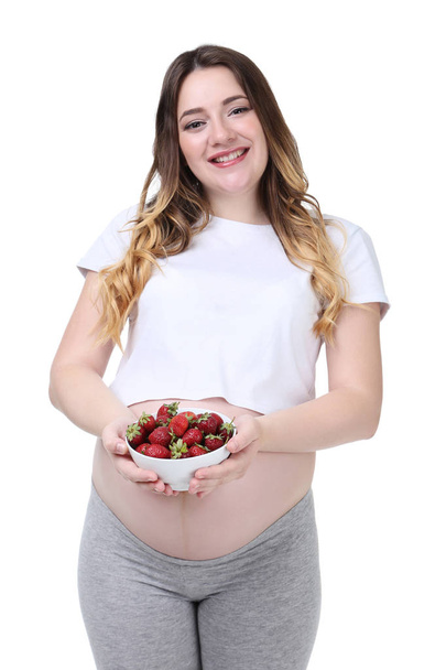 Beautiful pregnant woman holding bowl with strawberries on white background - Valokuva, kuva