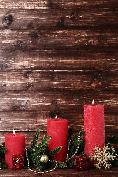 Red christmas candles with fir tree branches on brown background - Foto, Imagen