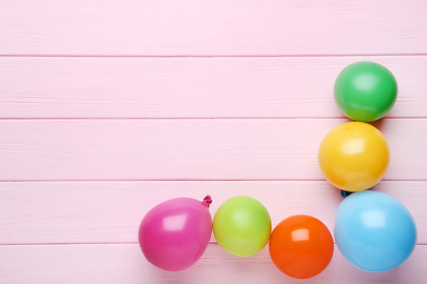 Colorful balloons on pink wooden table - Fotoğraf, Görsel