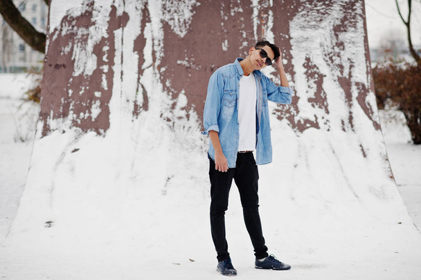 Casual young indian man in blue jeans shirt and sunglasses posed at winter day. - Foto, Imagem