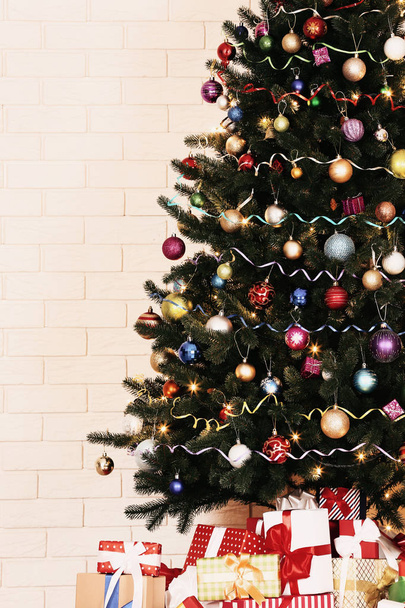 Árvore de Natal com decorações e caixas de presente no fundo da parede de tijolo
 - Foto, Imagem
