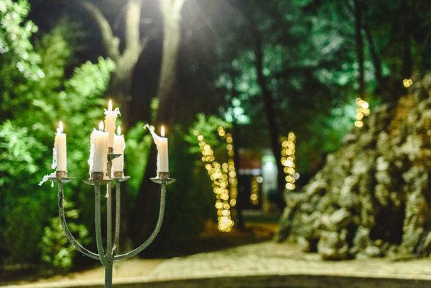 Свечи зажжены, чтобы осветить сад во время ужина ночью
. - Фото, изображение