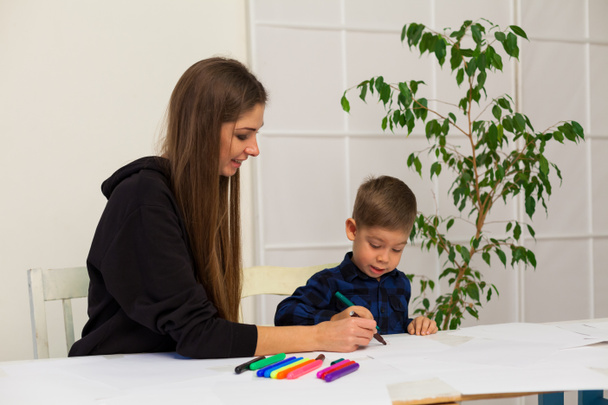 Маленький мальчик рисует маркеры из урока мать
 - Фото, изображение