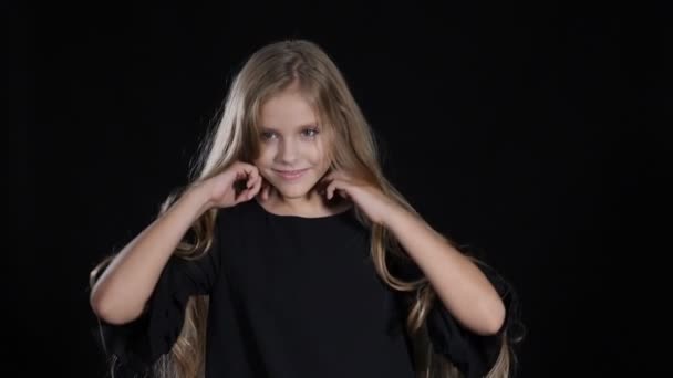 Portret van kleine model in studio geïsoleerd op zwarte achtergrond. Het aanraken van haar haren in slow motion, kijken camera, die zich voordeed. HD - Video