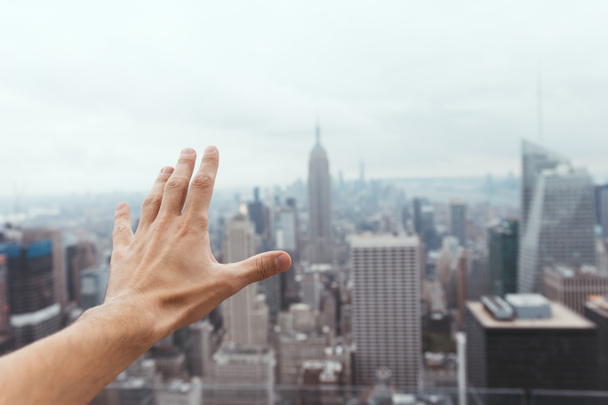 partial view of male hand and blurry new york city on background - 写真・画像