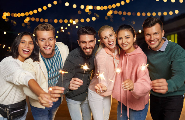 happy friends with sparklers at rooftop party - Foto, Imagem