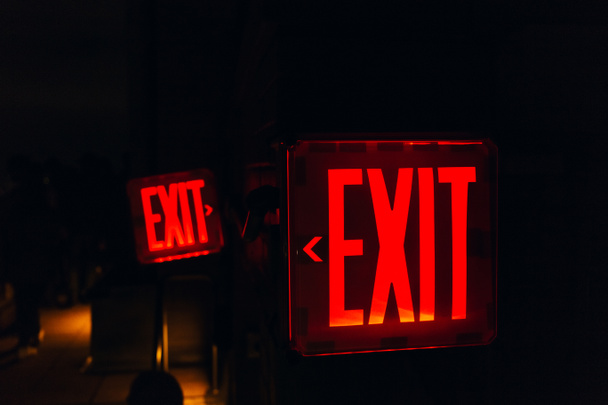 close up view of red exit sign on black backdrop - Fotoğraf, Görsel