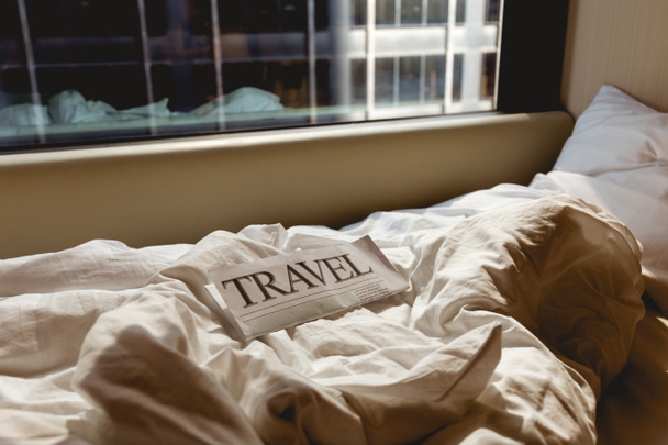 close up view of travel newspaper on bed in hotel room - Photo, Image