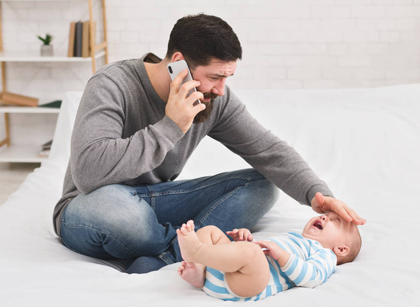 Father checking temperature and calling to doctor - Foto, imagen