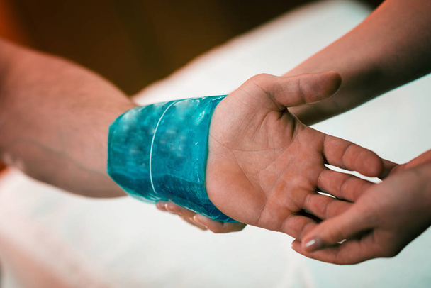 Holding the blue ice pack on the painful wrist - Fotografie, Obrázek