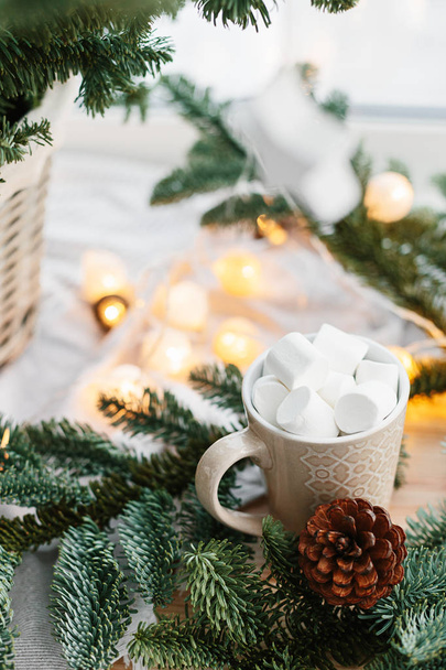 Spruce branches in basket and cup with cacao and marshmallow. Rustic new year christmas decoration at home, scandinavian interior - Foto, afbeelding