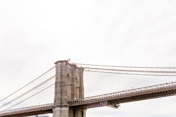 lage hoekmening van brooklyn bridge en bewolkte hemel op achtergrond, new york, Verenigde Staten - Foto, afbeelding