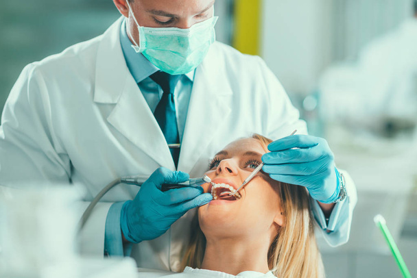 Молода жінка має стоматологічний огляд в клініці
 - Фото, зображення