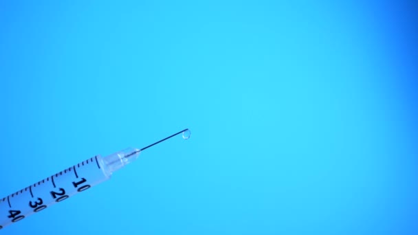 Syringe with drops closeup isolated on blue background - Footage, Video