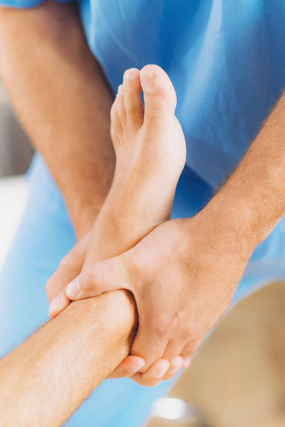 Fysiotherapeut genezende behandeling patiënt voet doen. Therapeut dragen blauwe uniform. Osteopathie, chiropractie voet aanpassing - Foto, afbeelding