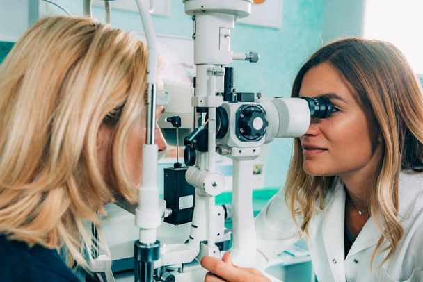 Silmälääkäri tutkii potilaan rakolampulla
  - Valokuva, kuva