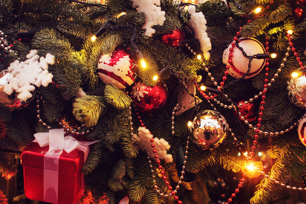 Искрящаяся новогодняя гирлянда на елке. Рождественская елка украшена золотыми и серебряными шариками
 - Фото, изображение