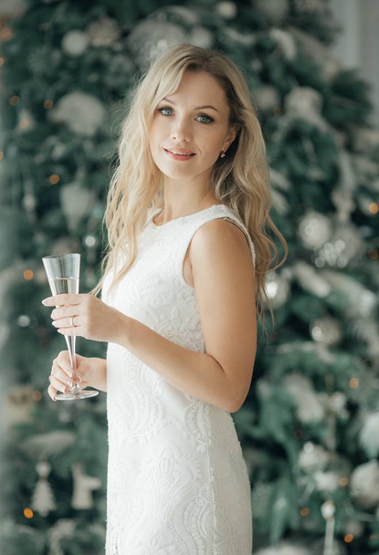 Beautiful woman in red dress near Christmas tree champagne  posing at home  - Foto, imagen