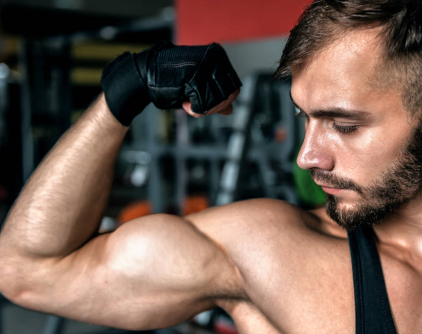 młody sportowiec patrzy na swoje bicepsy na siłowni - Zdjęcie, obraz