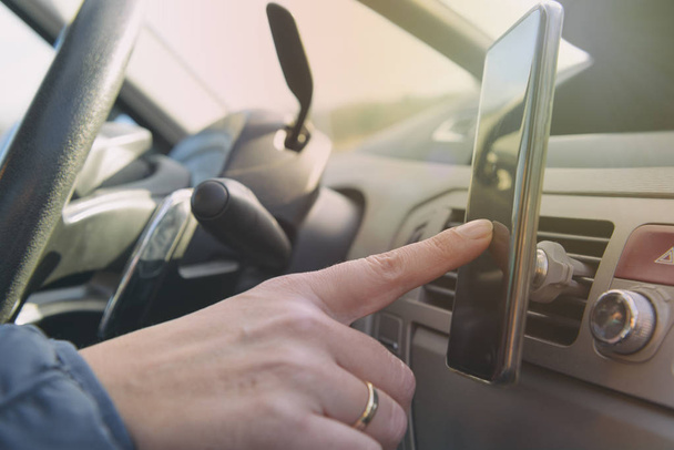 Frau nutzt Smartphone als Navigationsgerät während der Autofahrt. Konzept für riskantes Fahrverhalten - Foto, Bild