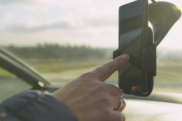 女性が車を運転中にナビゲーションとしてスマート フォンを使用して。危険な運転の動作概念 - 写真・画像