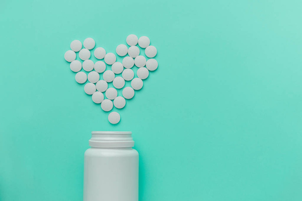 Medicamentos blancos, píldoras redondas en forma de corazón aisladas sobre fondo turquesa
. - Foto, Imagen