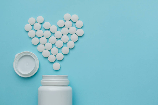 Medicines white, round heart shaped pills isolated on blue background. - Foto, Imagen