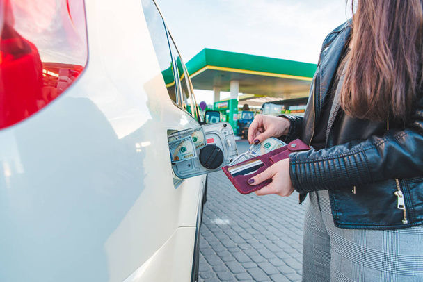 財布を持つ女性。車の燃料タンクにお金を置きます。コンセプトを燃料補給車 - 写真・画像
