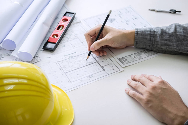 Építőmérnöki vagy építész kéz dolgozik tervrajz ellenőrzés a munkahelyen, miközben ellenőrzi az információs rajz és vázlat az építészeti projekt munka. - Fotó, kép