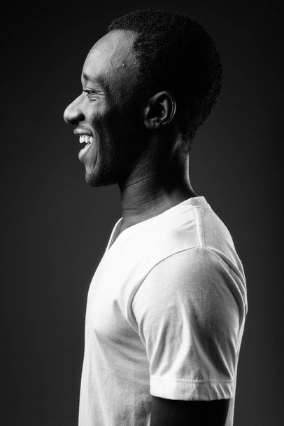 Profile view portrait of young African man smiling in black and white - Foto, afbeelding
