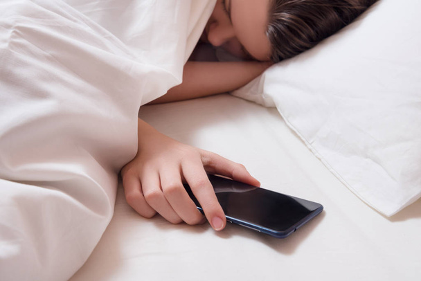 Young girl under the blanket with smart phone in the hand - Foto, Imagem