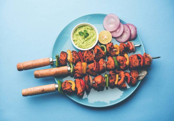 grilled chicken tikka on skewers.  served in a plate with green chutney and onion. Selective focus - Foto, Imagen