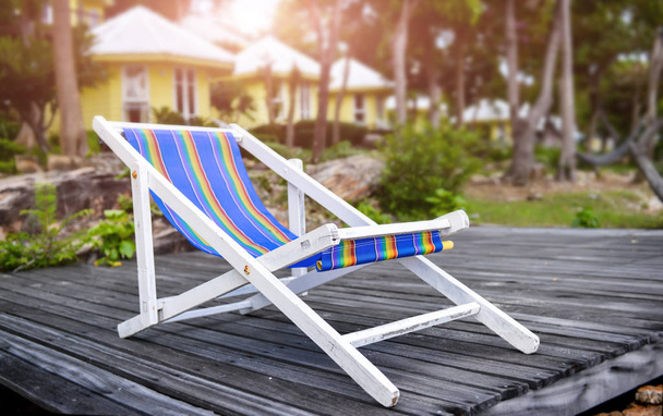 Білі дерев'яні пляжні стільці на морському дерев'яному балконі з зовнішнім освітленням сонця
. - Фото, зображення
