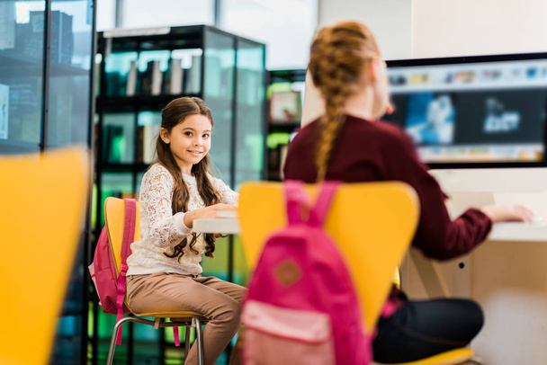 чарівні школярки використовують настільні комп'ютери в бібліотеці
  - Фото, зображення