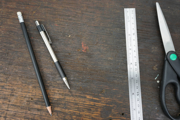 flach mit Stift, Bleistift, Lineal und Schere auf alten hölzernen Tischplatten - Foto, Bild