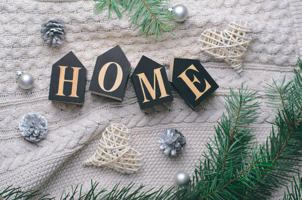 Cozy Home Winter Concept, Pine Branches and Home Letters on Beige Knitted Background, Top View - Foto, Bild