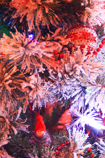 Svislý střílel na bílý umělý strom a jeho vánoční ozdoby. Malý skřítek v vlny a pěkně červený míček se zlatou hvězdou a perlový náhrdelník - Fotografie, Obrázek