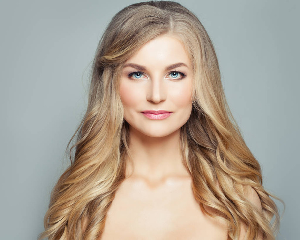 elegante blonde Frau mit langen gesunden lockigen Haaren und klarer Haut. Gesichtsbehandlung, Wellness- und Kosmetikkonzept - Foto, Bild