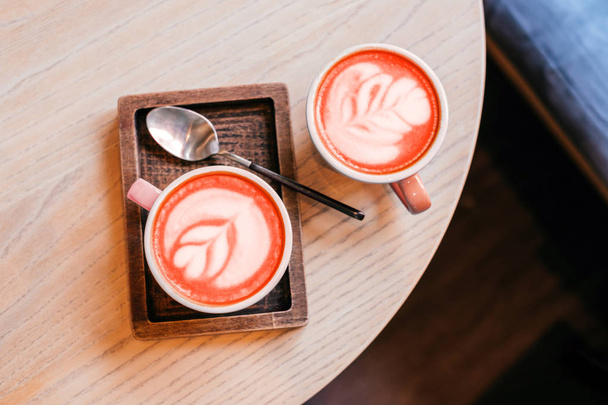 Két kék csésze cappuccino, gyönyörű latte art az asztalon, a fából készült lemez, kanállal. - Fotó, kép