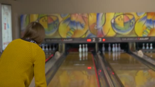 Menina caucasiana feliz jogando boliche em suéter amarelo
 - Filmagem, Vídeo