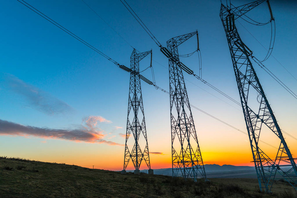 arancio tramonto cielo e trasmissione pali elettrici in campo rurale
  - Foto, immagini